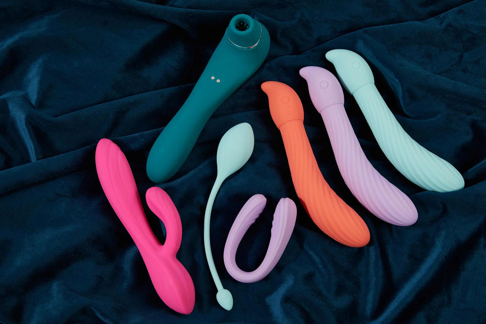 Colorful silicone vibrators arranged on white fabric