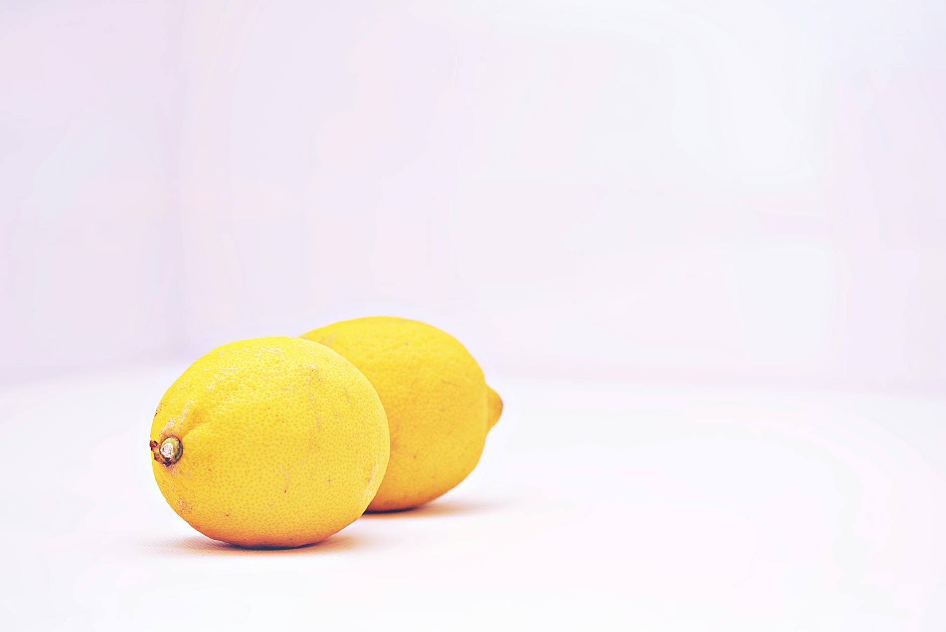 Two vibrant lemons on a minimalistic white background, symbolizing precision and clarity
