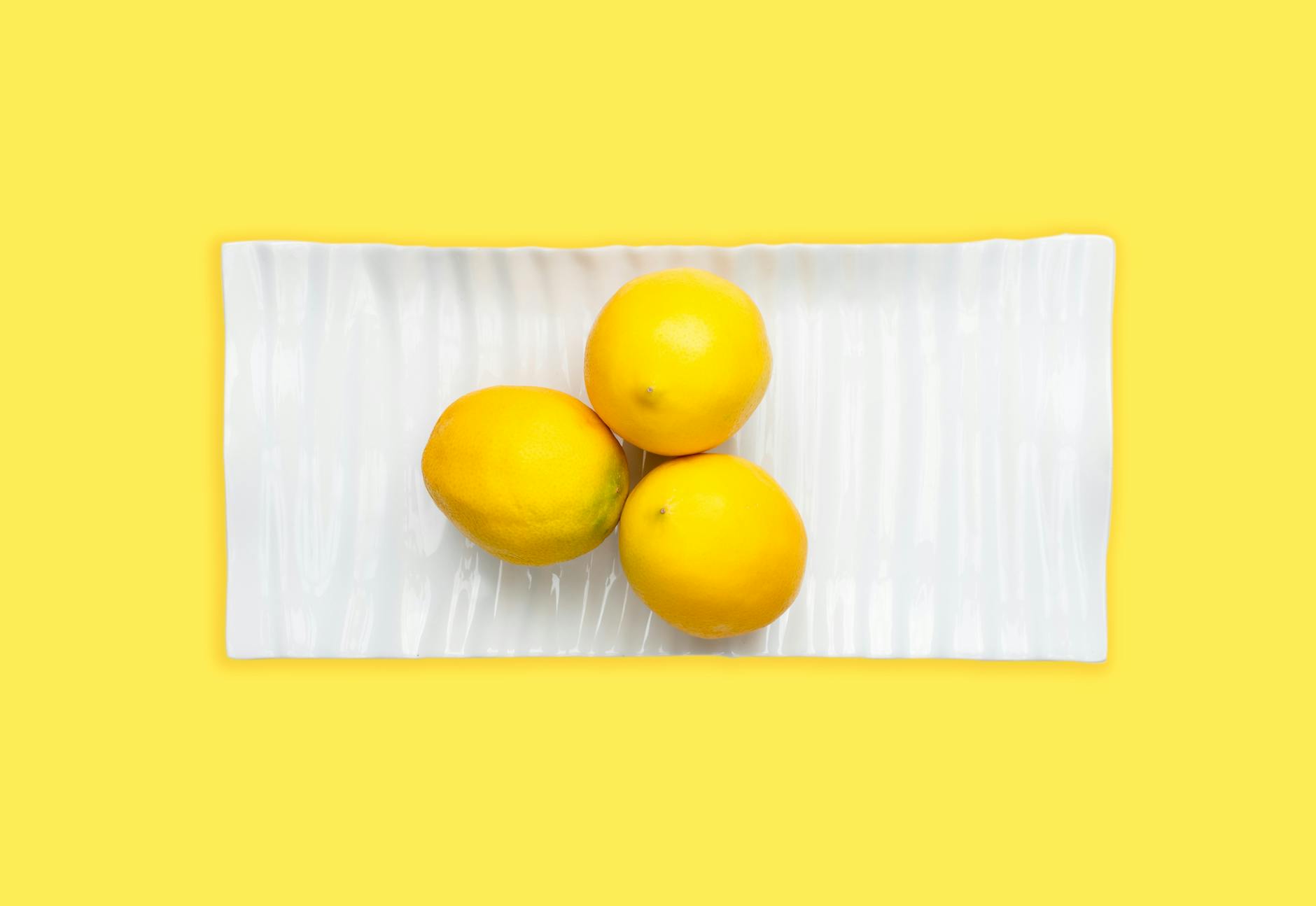 Hand holding a lemon on soft pink background, symbolizing intimacy and desire
