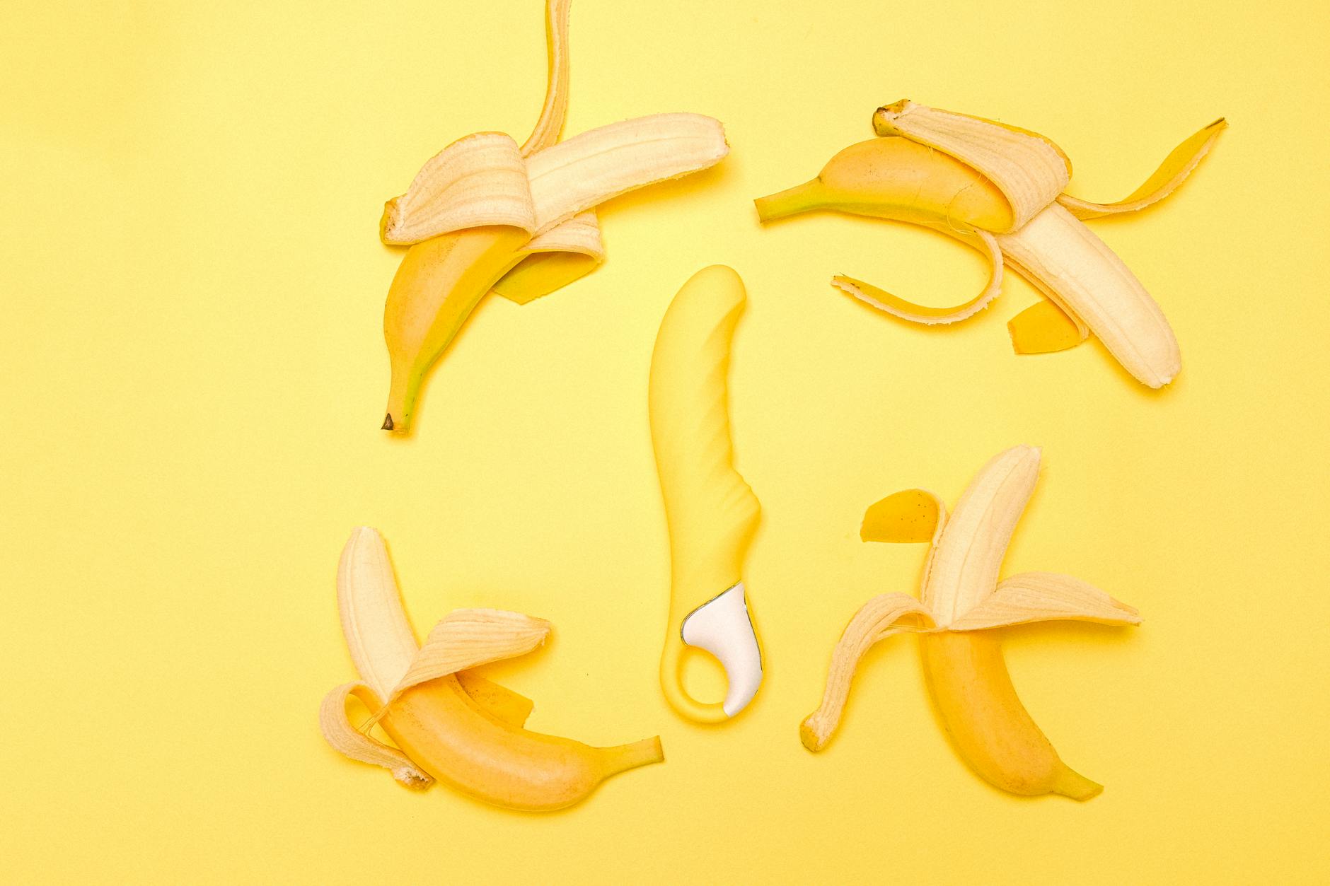 Lemon clitoral vibrator surrounded by fresh lemons on yellow background