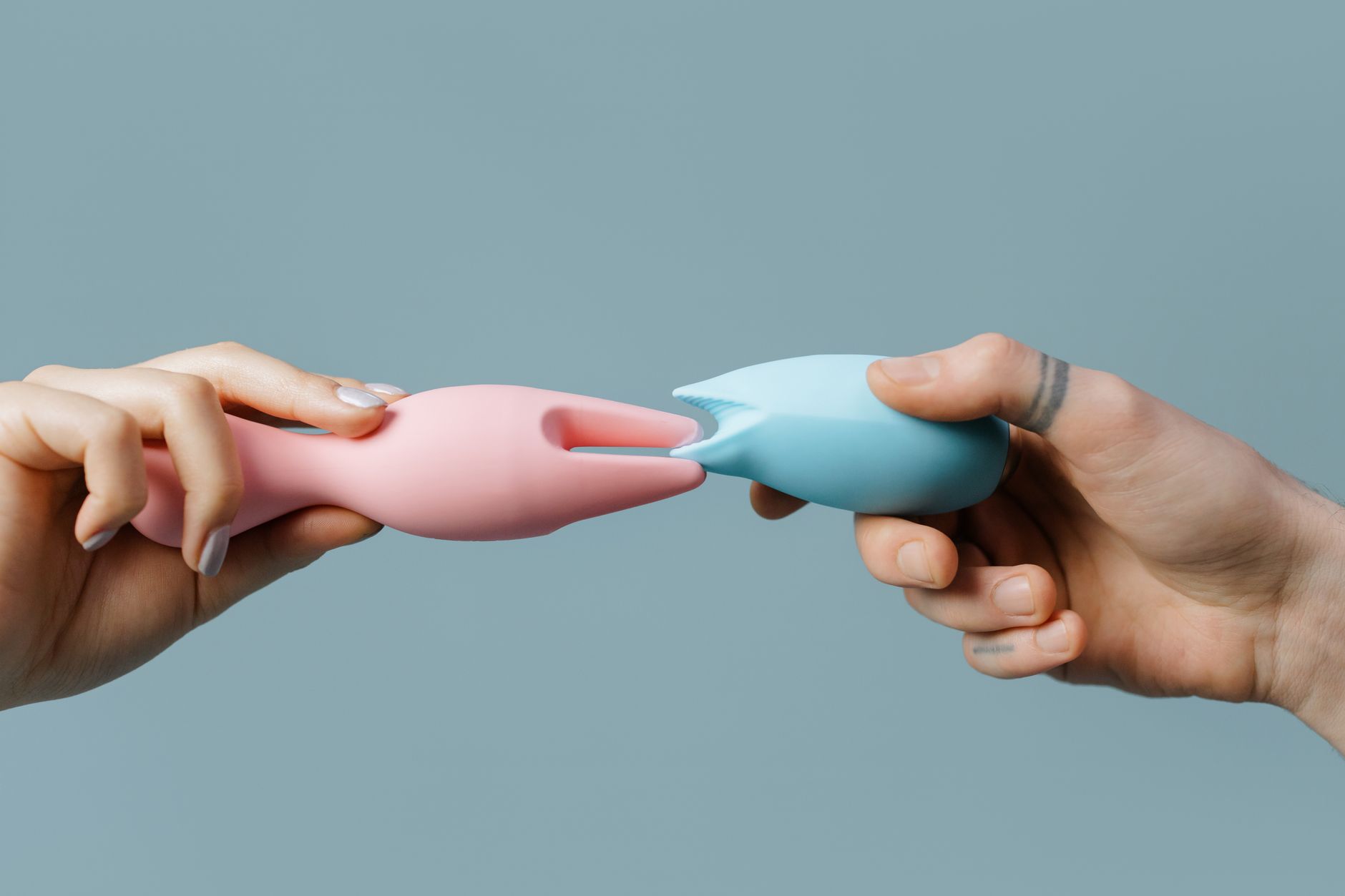 Hands holding a colorful silicone vibrator in natural light