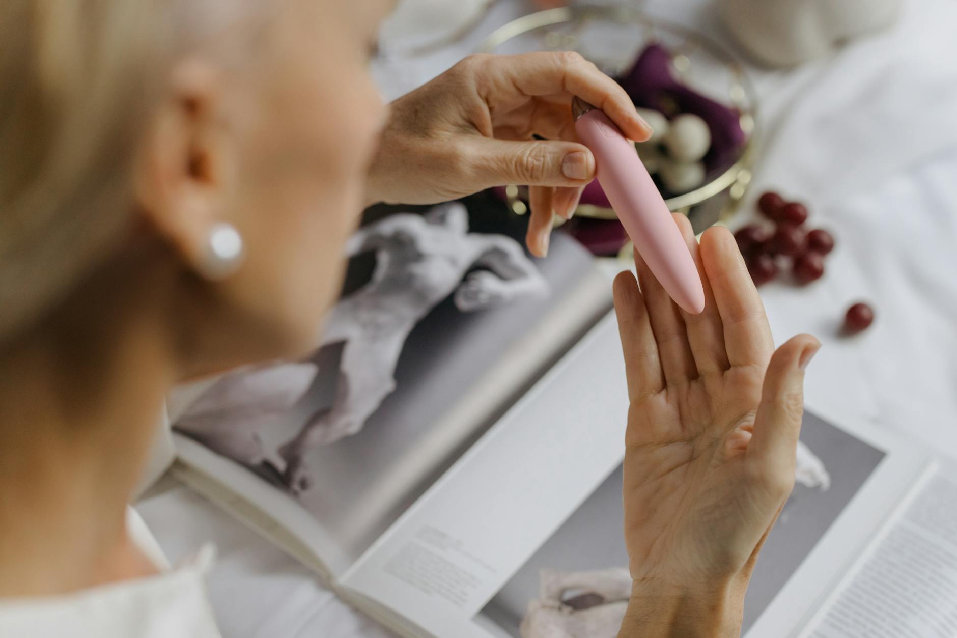 A close-up of hands holding a pink vibrator, with personal intimacy items nearby, representing pleasure after IUD insertion.