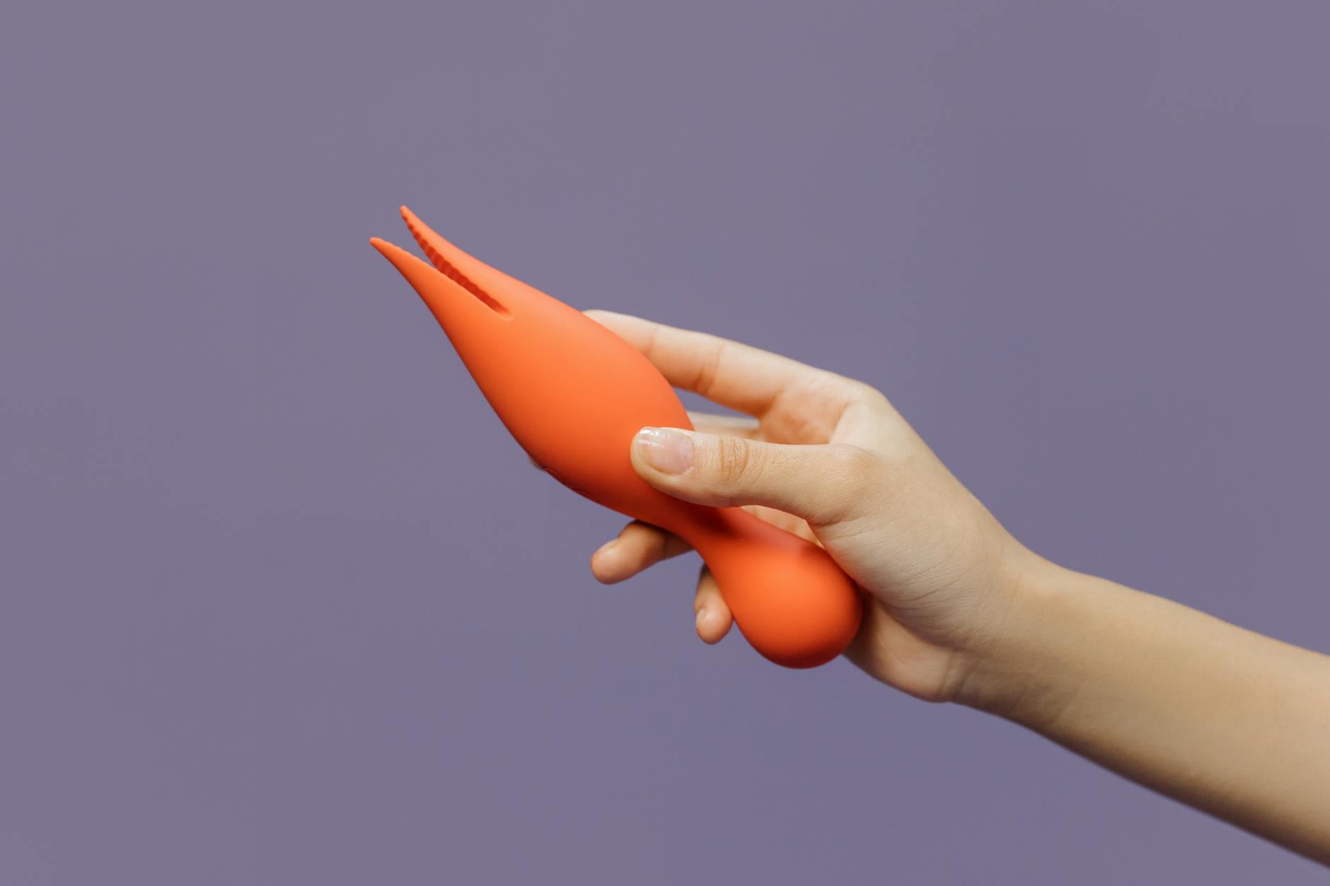A blue silicone vibrator held in hand against a solid purple background, promoting self-love and sexuality