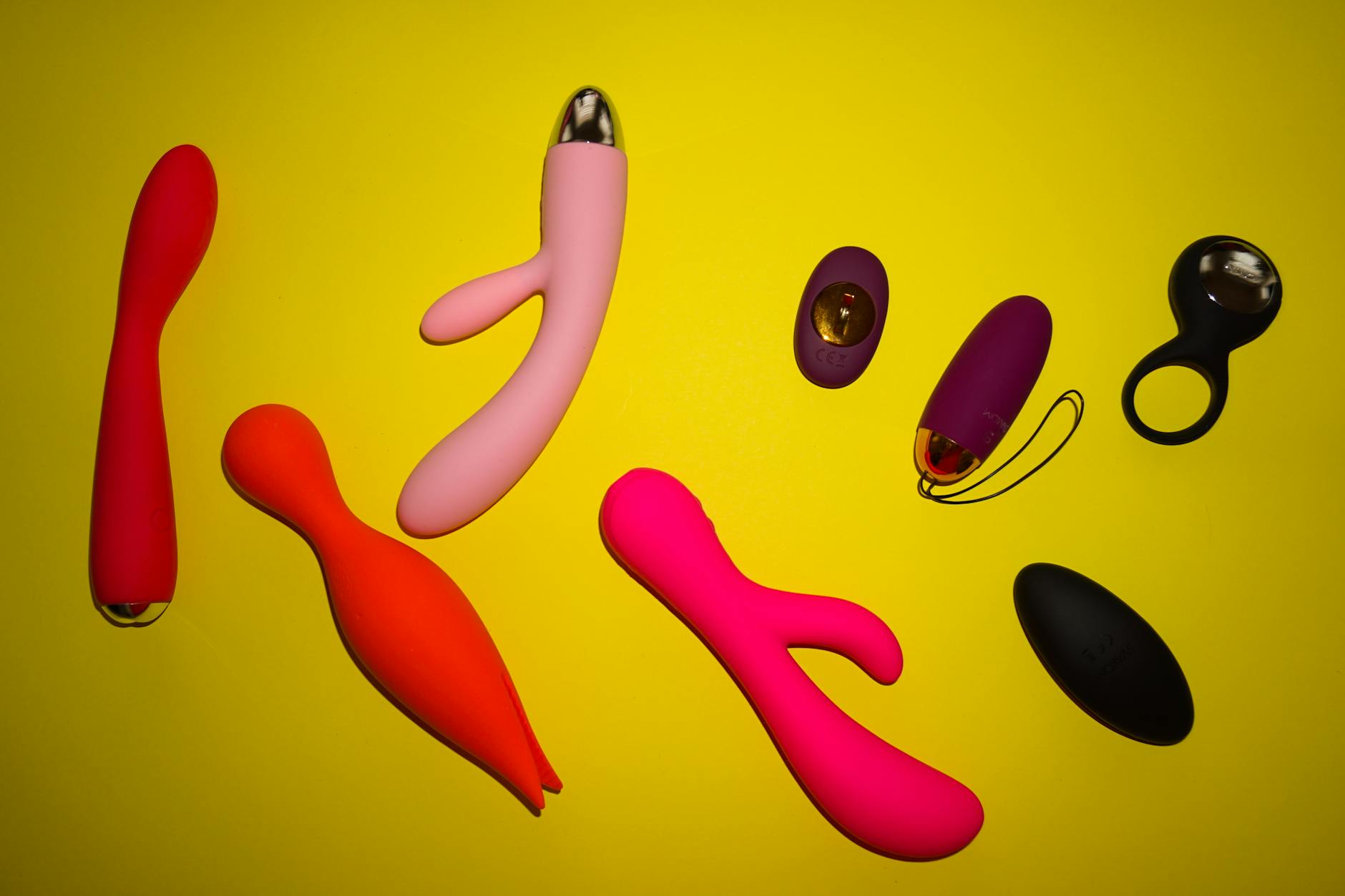 Hand holding an orange vibrator against a minimalistic purple backdrop