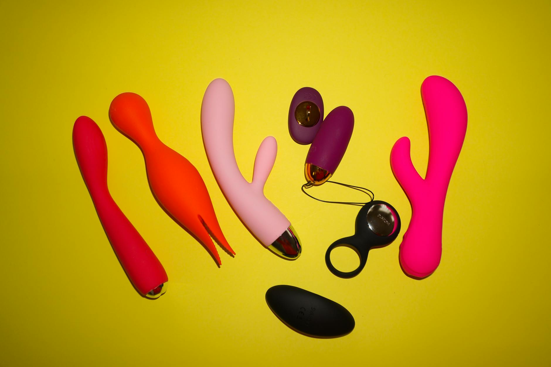 Collection of colorful vibrators arranged on a bright yellow background