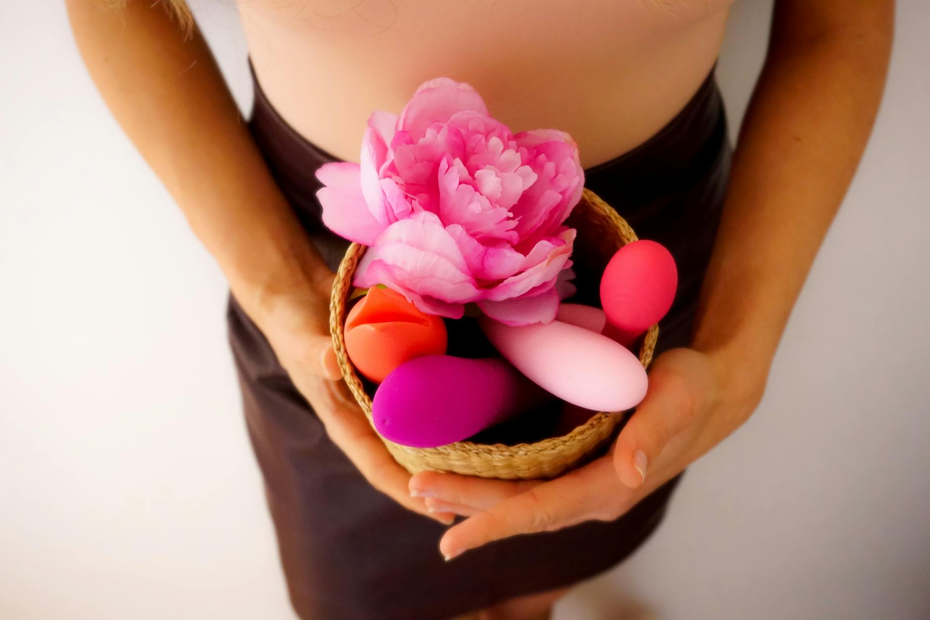 A basket containing colorful adult toys and a pink flower, representing the beginning of a pleasure journey